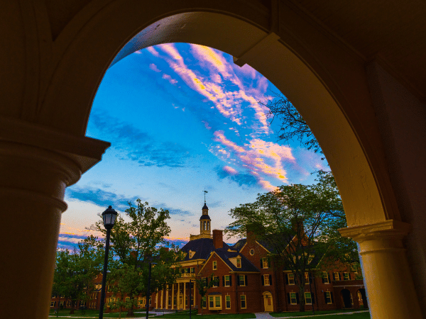 Blue and orange sunset seen through an archway of MacCracken Hall