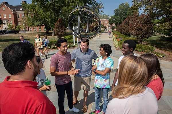 A group of students talk in front of the Tri-Delt Sundial.