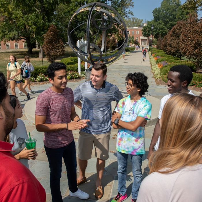 Some multicultural students meeting near the university bronze sundial