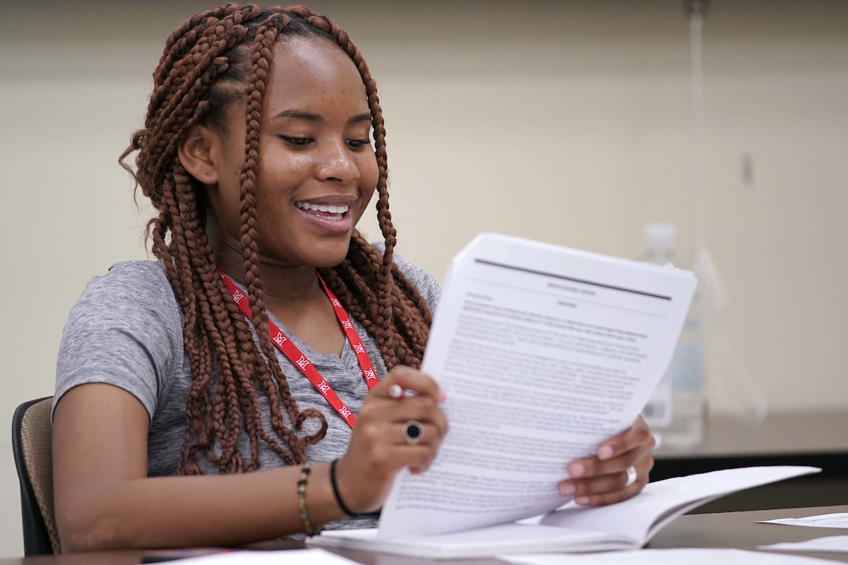 A student smiles while reading a print out in class.