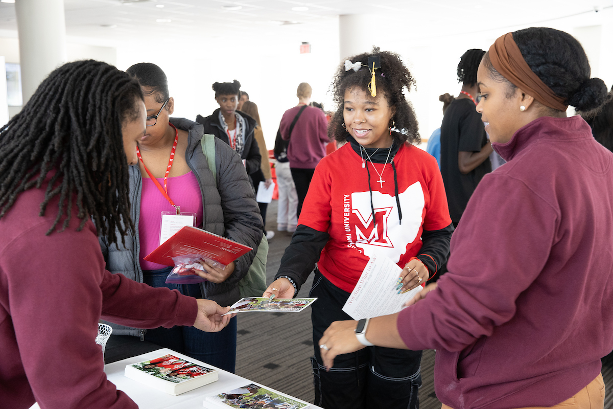 A student hands out flyers to Bridges Program participants during an event.