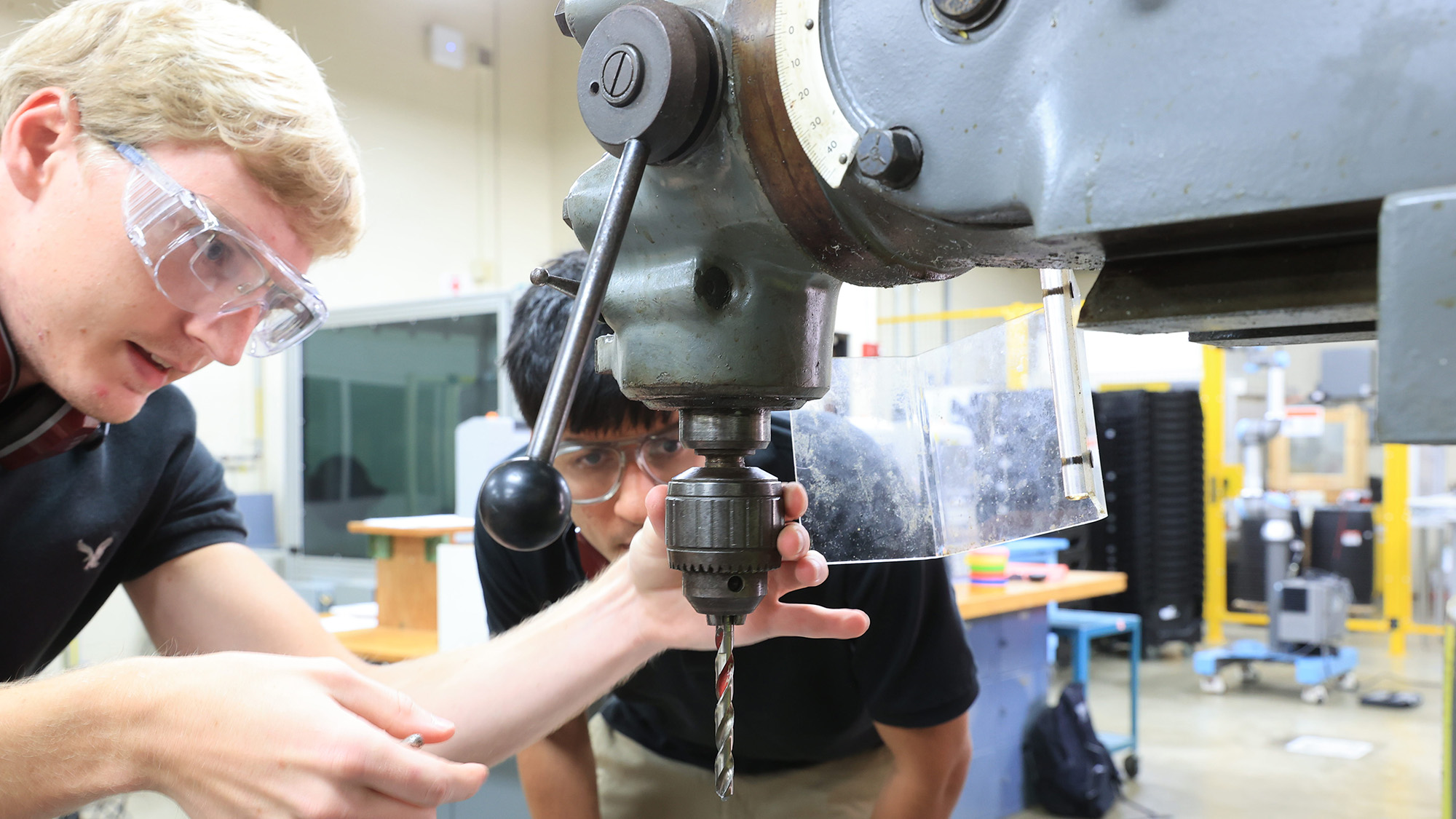 A student watches a professor operate an instrument in a lab.