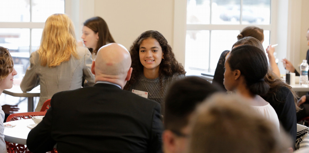 A student smiles while speaking with a campus guest at a luncheon.