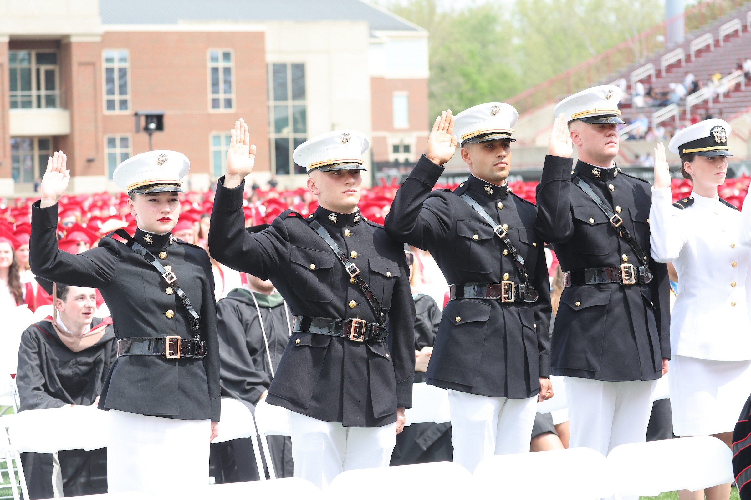 Five ROTC cadets raise their hand while taking an oath at a Miami commencement ceremony.