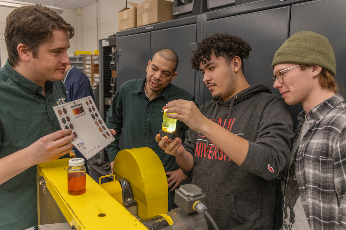 A group of students look at a vial in a lab.