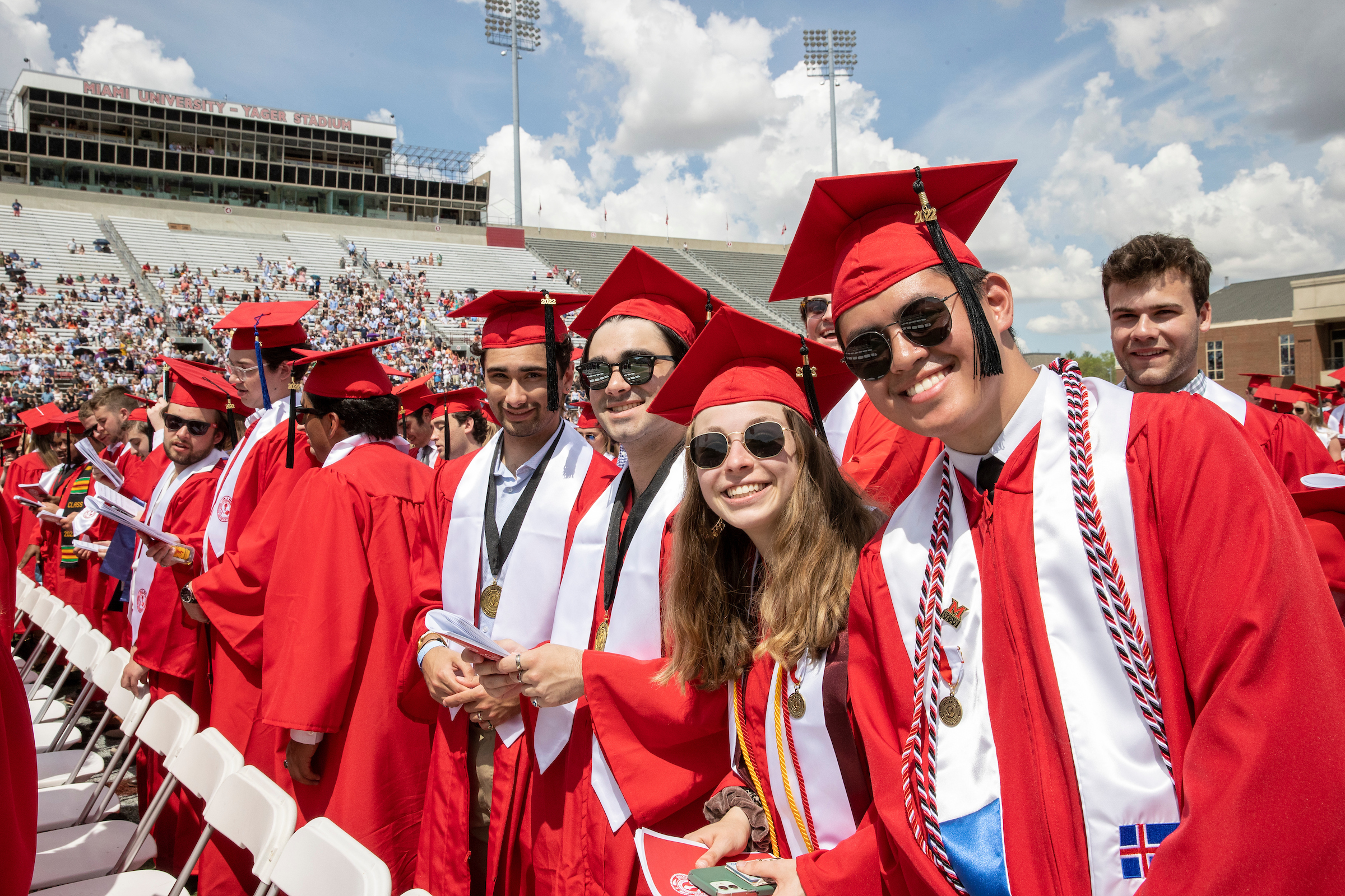 Two graduates smile for the camera at their commencement ceremony.