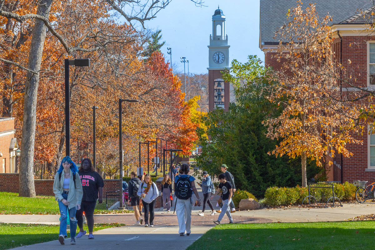 Students walk to class in the fall with the Bell Tower in the background.