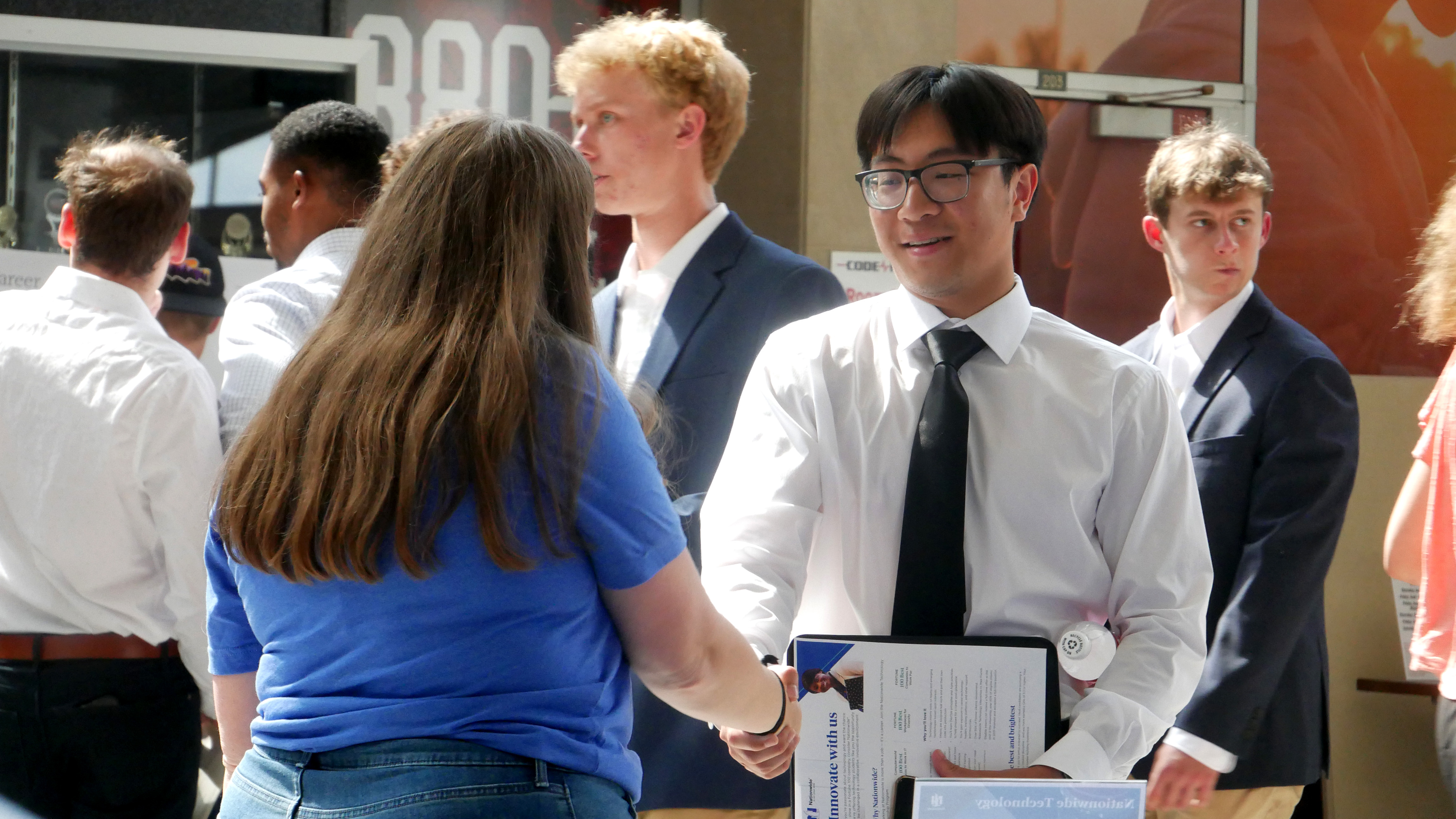 A student shakes hands with an employer at a career fair.