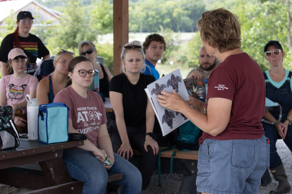 A professor addresses a group of students outside.