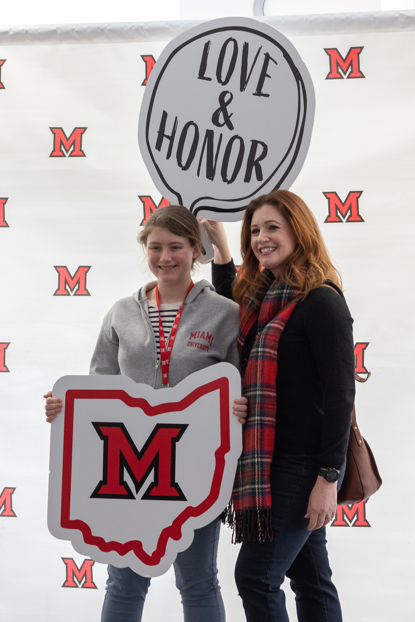 A student and parent pose in front of a Miami backdrop with "Love and Honor" and "Miami Ohio" signs.