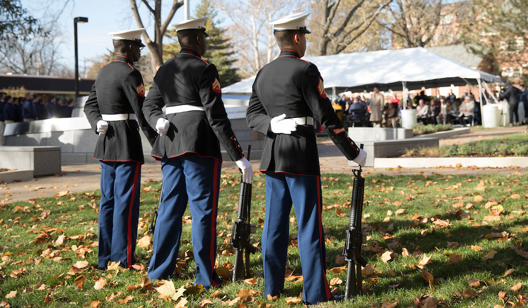 An honor guard stands at attention before giving a three-volley salute.