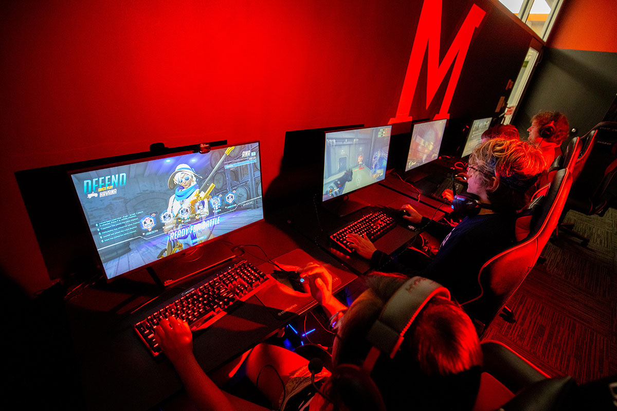 students in gaming room with red lighting playing video games