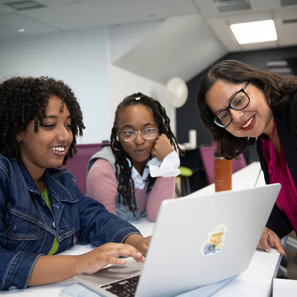 Three women looking at an AI prompt response on a laptop.