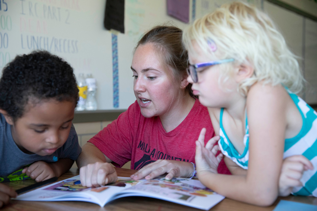 A teacher reading up close with two young students.