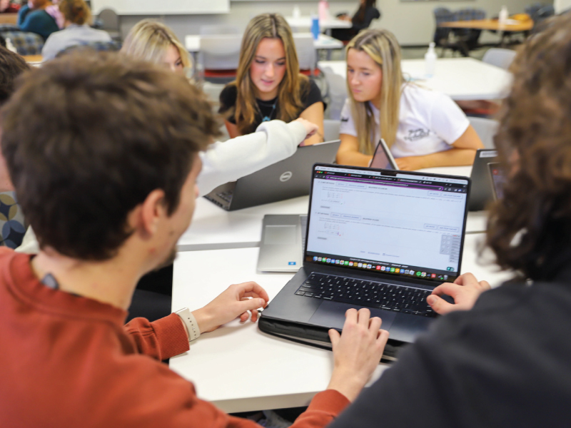 A group of ECA students sitting at a table working on their laptops.