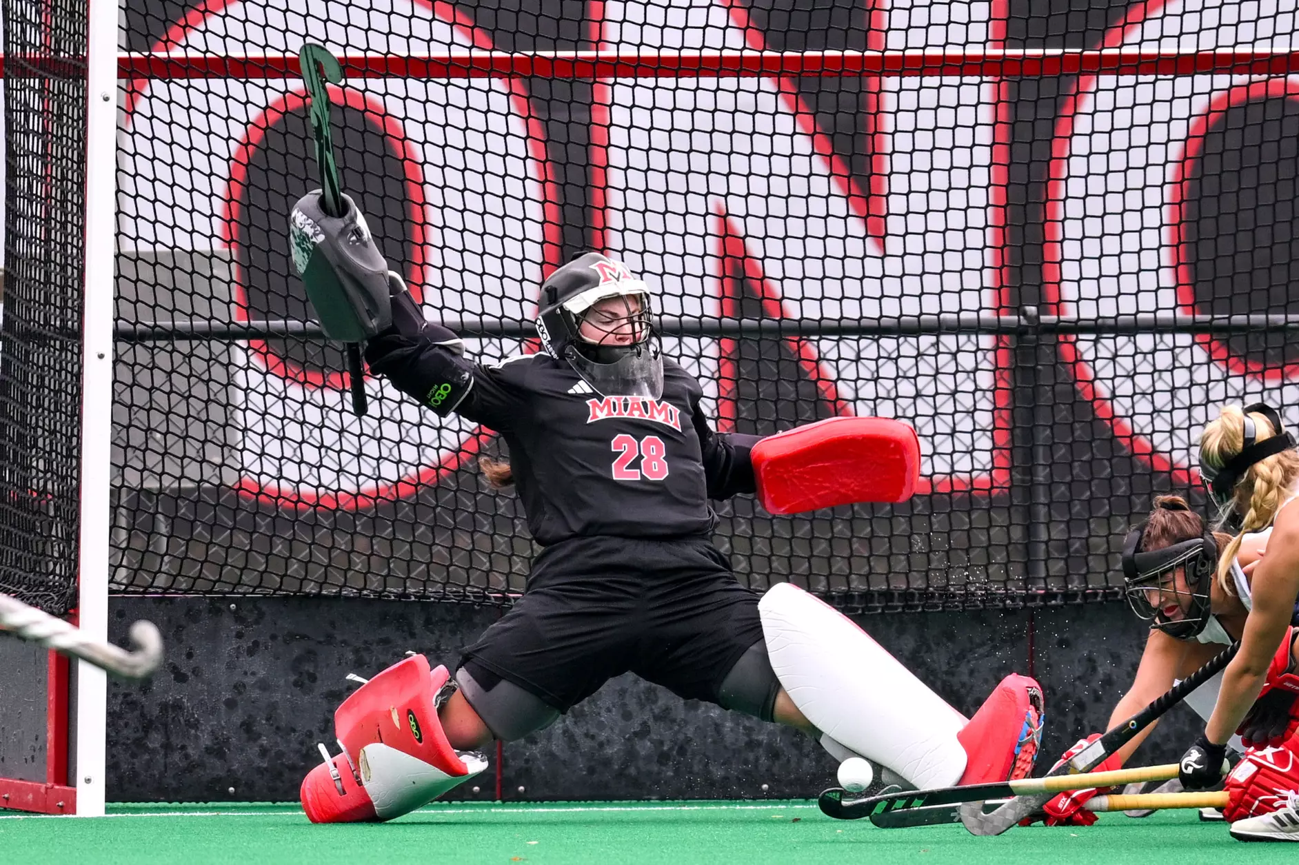 Isabelle Perese guards the field hockey goal and prevents the other team from scoring, throwing her leg out to block the ball.