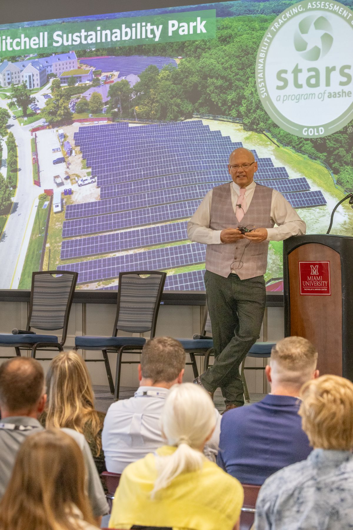 President Crawford stands before his presentation title slide about the new sustainability park on the Oxford Ohio campus.