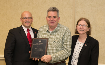 David Berg with President Crawford and Phyllis Callahan to the right with his distinguished service award