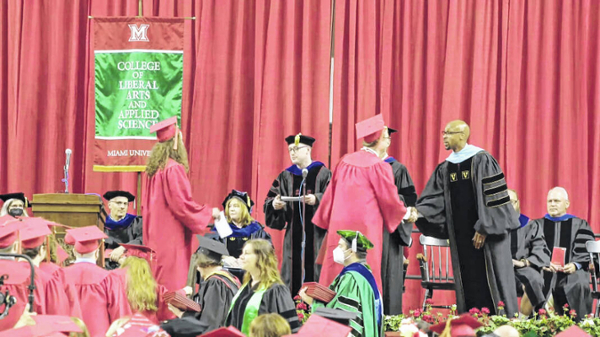 Mark R. Smith, of Sidney, in red cap and gown, receives his diploma from Ande Durojaiye, vice president and dean of the Miami University College of Liberal Arts and Applied Science, during ceremonies, May 15, 2022 in Oxford.