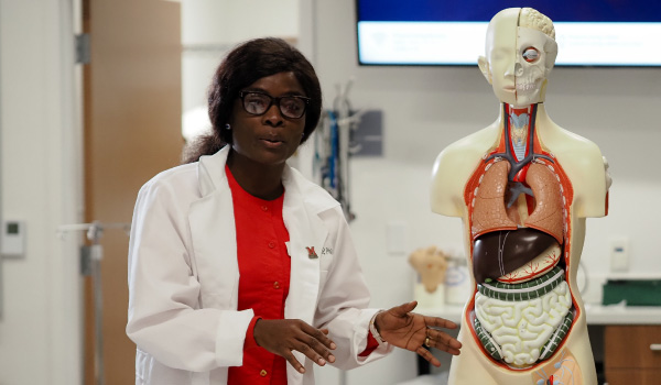 A student standing next to a skeleton dummy talking to the class