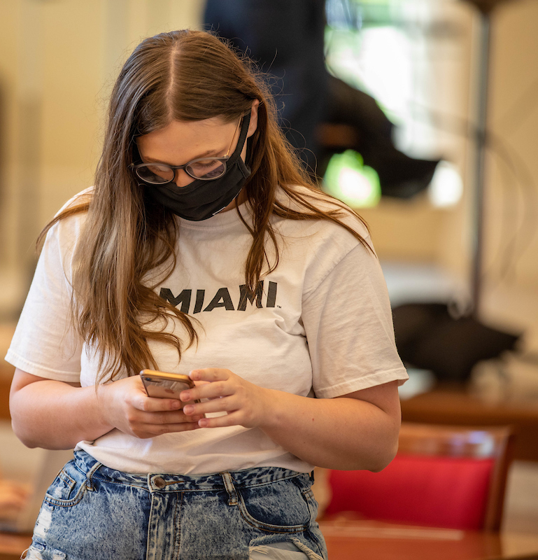 Student with mask on looking at phone