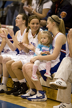 Shandar Musselman Thompson on bench during game with other players and her daughter McKayah.