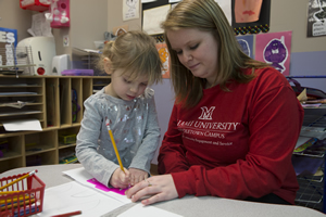 Pre-k student instructor using a stencil with a child.