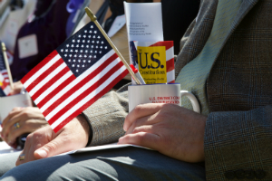 Photo of American flag and a copy of the U.S. Constitution in a cup on someone's lap