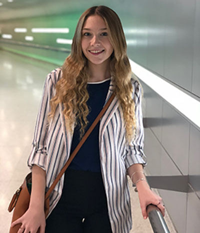 Image of Alexandria Fletcher standing in a hallway holding a railing.