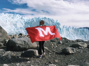 Alaezsha Mayo with a Miami Flag draped across her shoulders and mountains with snow in the background in Argentina