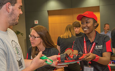 A orientation leader handing a student his welcome packet.