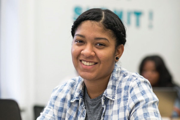Student sitting at their desk smiling towards the camera