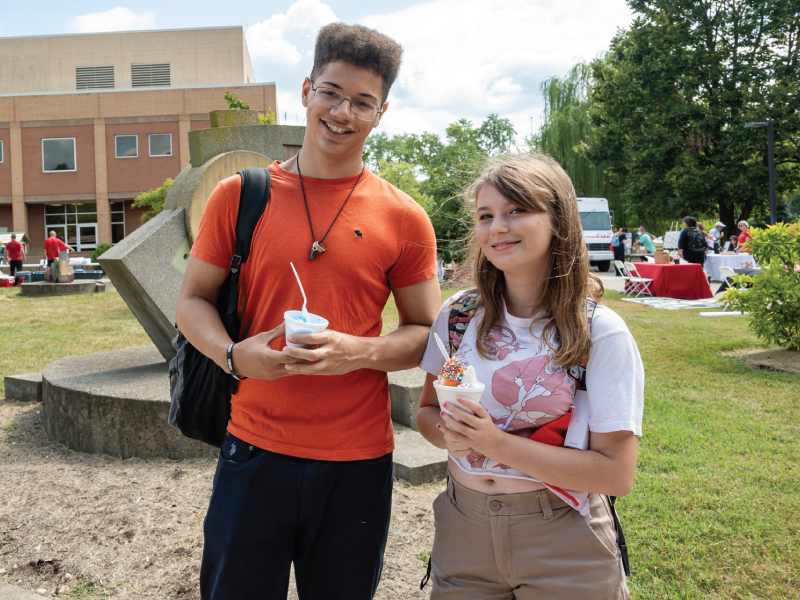 一名男生和一名女生在汉密尔顿分校秋季庆典上吃冰淇淋。