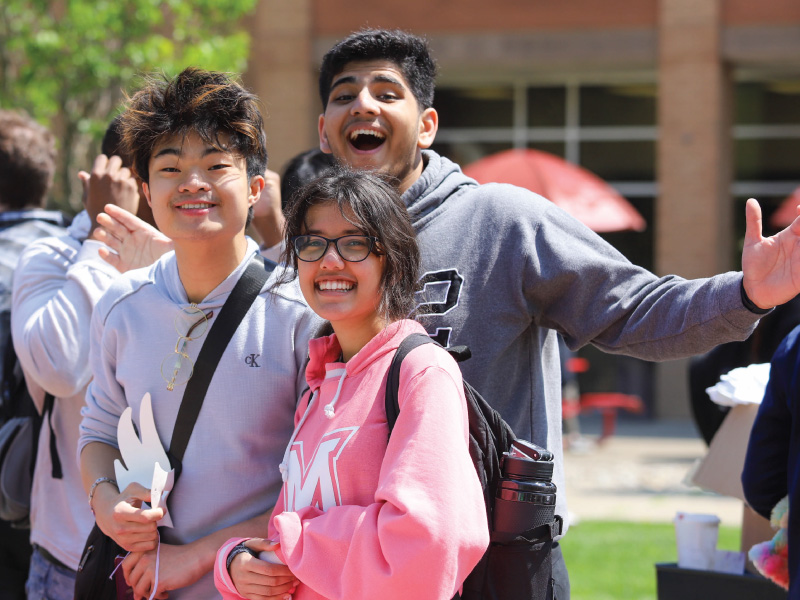 Tres estudiantes se divierten al aire libre durante el Festival de Primavera en el patio interior del campus de Hamilton.