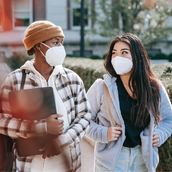 2 Students walking outside on campus with masks on.