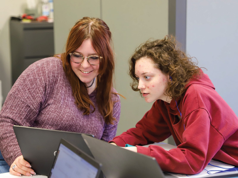 2 students working on a their laptops in the ECA room. 