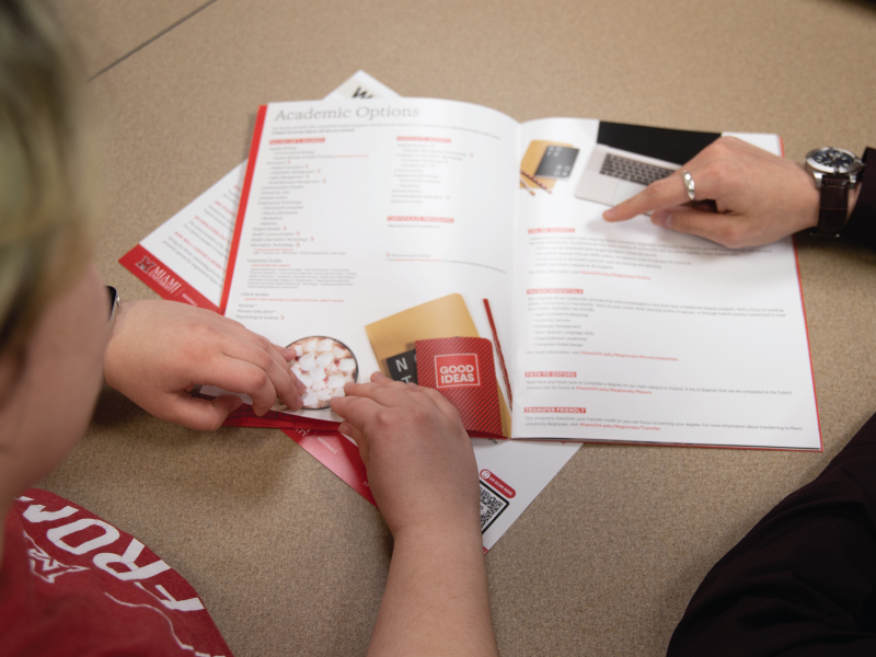 Una consejera de transferencias con un bloc de papel en la mano hablando con un estudiante sobre el proceso de admisión.
