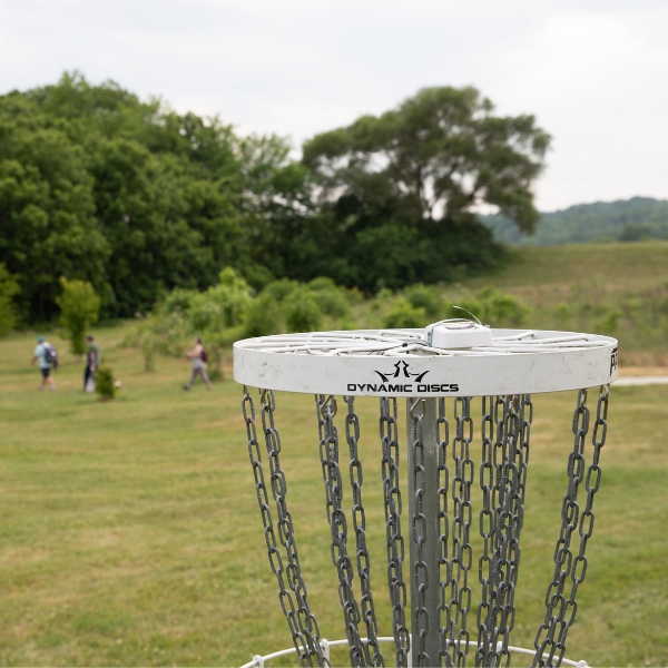 A player throwing a disc towards the disc golf basket.