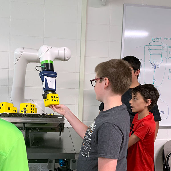 Campers working with a robotic arm to move objects