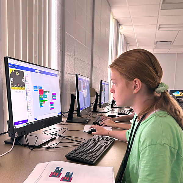 A female camper using code to build a computer game