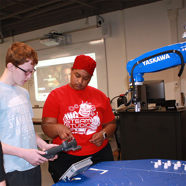 Leader in training programming a robot arm