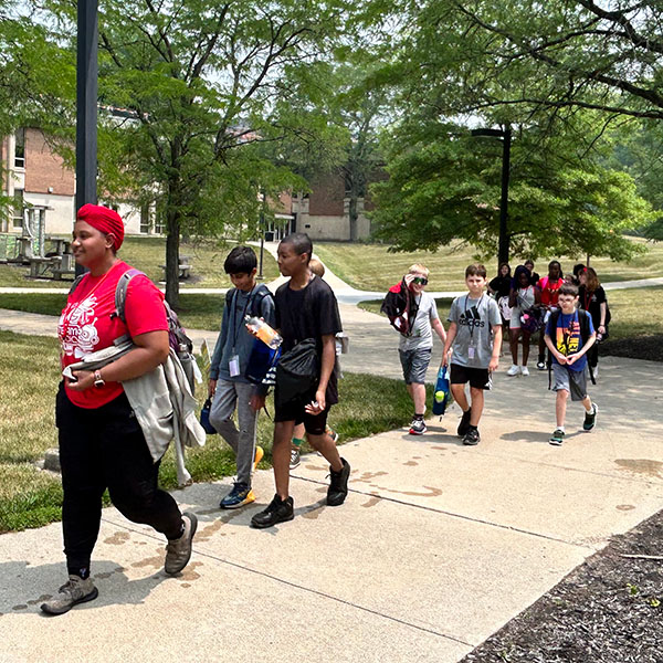 STEAM counselor leading a group of campers to an activity
