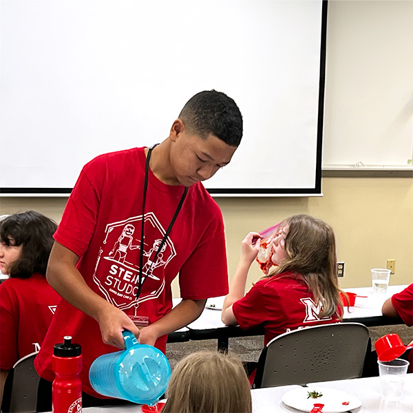 Leader in training helping campers assemble robots