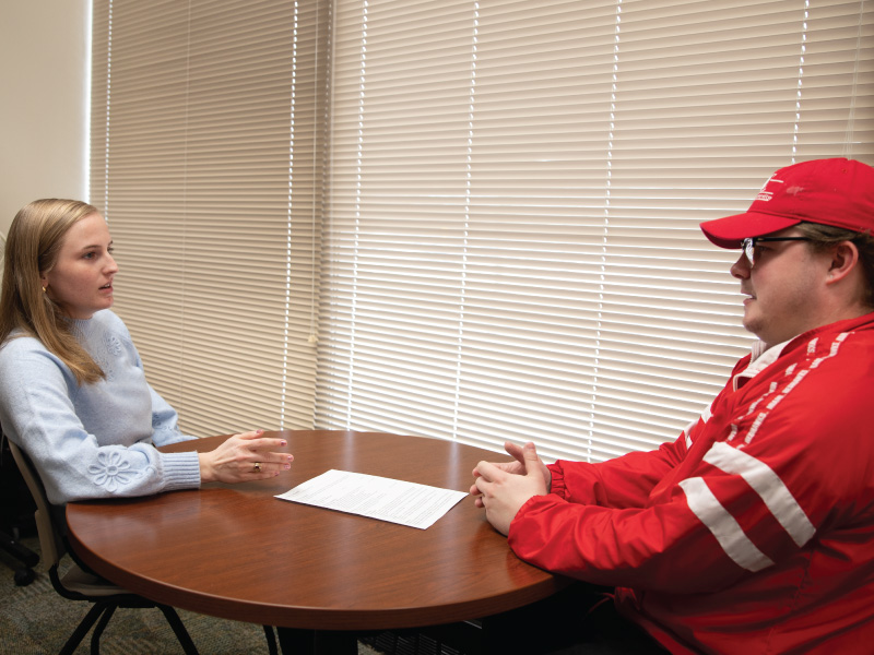 Career Services staff member Anna talking with a student and showing them a booklet on majors.