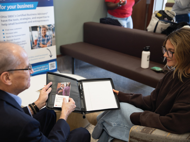 Career Services staff member Steve Whayne talking with a student and giving them a booklet on career planning.