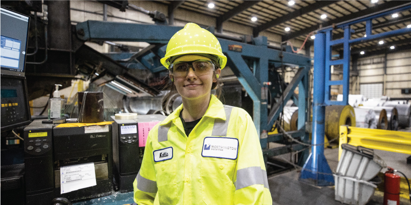 Work+ student in a hard hat and bright yellow top from Worthington Steel. 