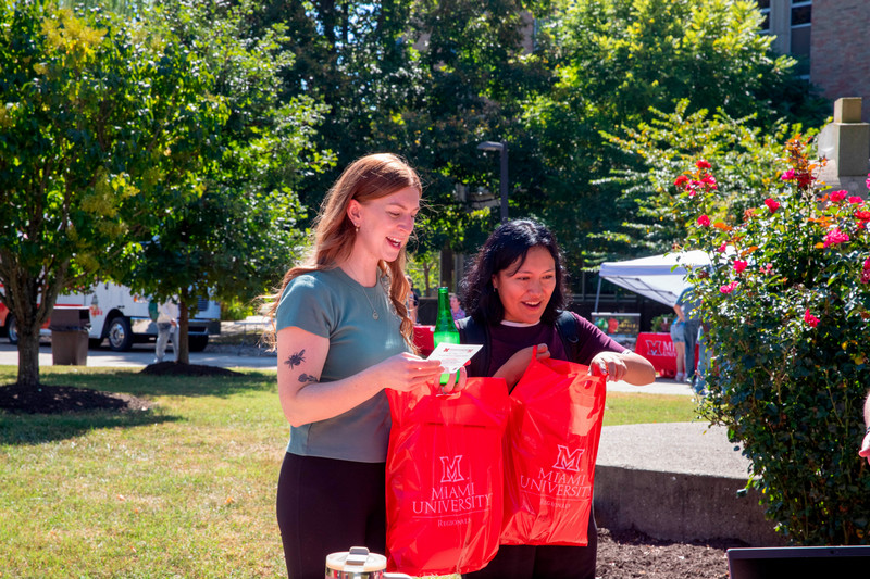 2 students holding red bags with Miami Regionals logo on them