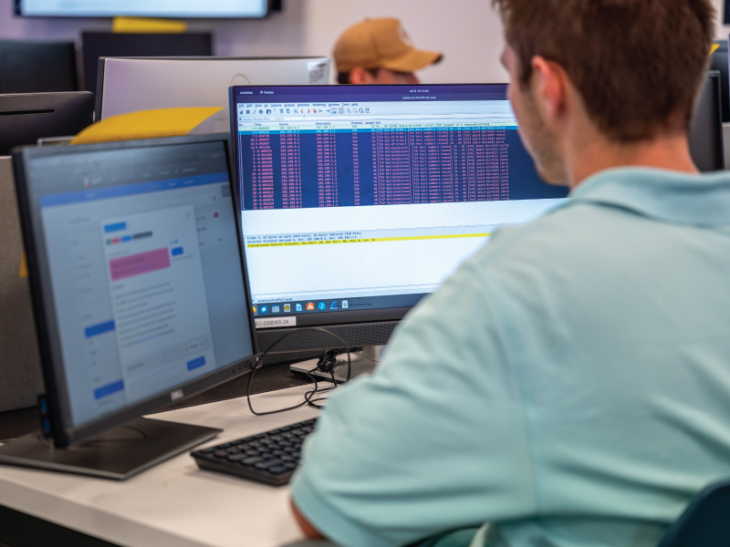 A student sitting in a computer lab with 2 screens up. 