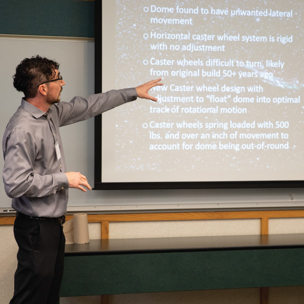 Student pointing towards a powerpoint presentation.