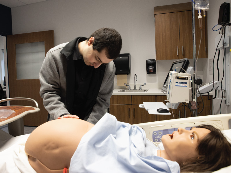 Lab coordinator placing a pregnant belly onto the sim manikin.